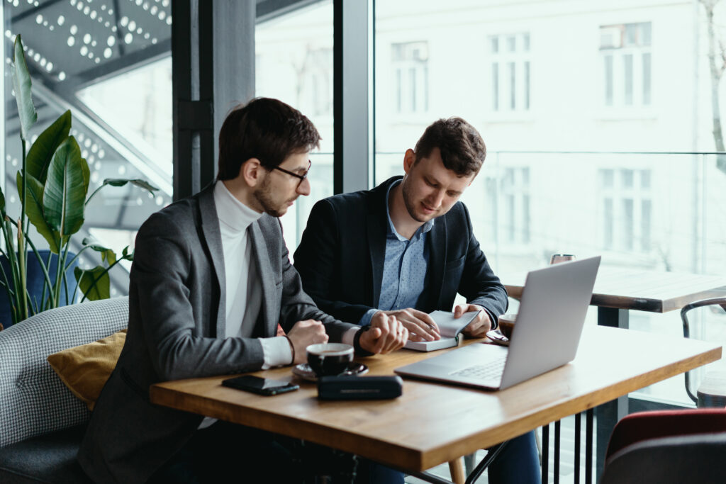 two young businessman having successful meeting restaurant scaled